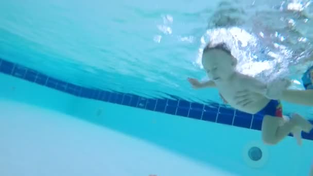 Un garçon nage sous l'eau, attrape un jouet sous l'eau, gros plan . — Video