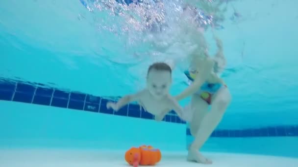 Bebé toma un juguete desde el fondo de la piscina, de cerca . — Vídeos de Stock