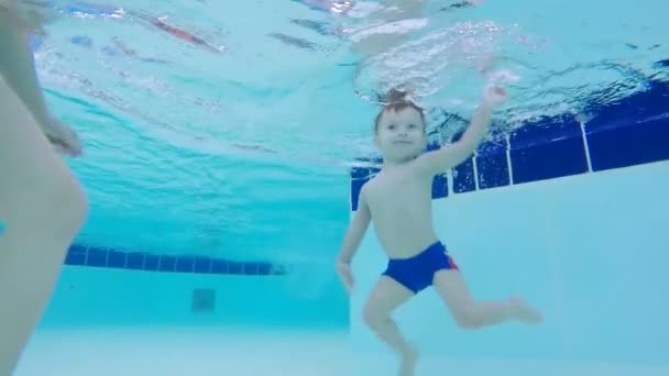 Een gelukkige baby onderwater zwemmen in een zwembad, close-up. — Stockvideo
