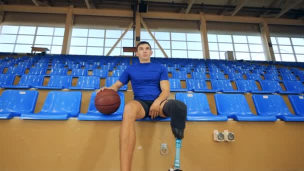 Een basketbalspeler met prothetische been zit, close-up. — Stockvideo