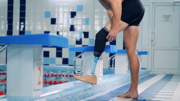 Eine Person zieht am Pool eine Prothese an, Seitenansicht. — Stockvideo