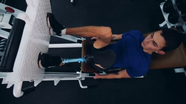 Un sportif avec une prothèse de jambe s'entraînant dans une salle de gym, vue de dessus . — Video