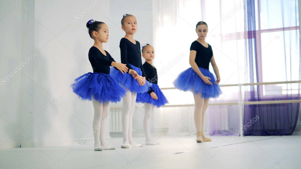 Ballet lesson with a female coach instructing little girls