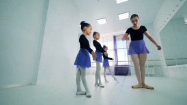 Bir öğretmen küçük balerinler pozisyonları gösterir..