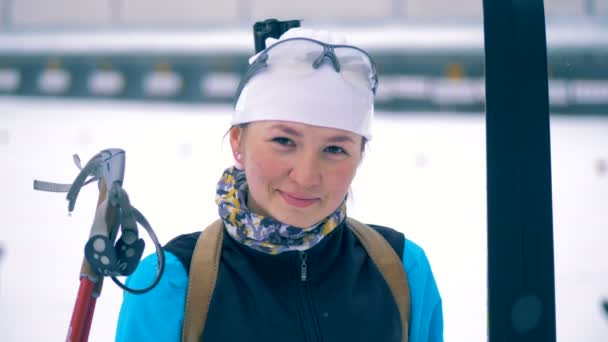 Женщина-биатлонистка стоит и улыбается в камеру — стоковое видео