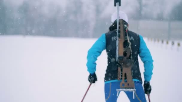 Veduta posteriore di una biatleta donna che sciava nella nevicata — Video Stock