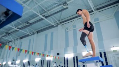 Bir erkek bir protez bacak ile bir havuzda yüzmek için hazırlanıyor