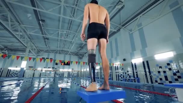 Um homem com uma perna biónica está a aquecer numa piscina. — Vídeo de Stock