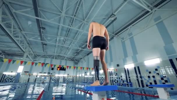 Schwimmbad und ein Mann mit Roboterbein beim Aufwärmen — Stockvideo