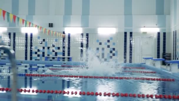 Σε εσωτερικούς χώρους, πισίνα και ένας άνθρωπος με ένα βιονικό πόδι κολύμβηση κατά μήκος — Αρχείο Βίντεο