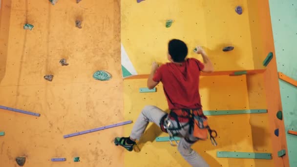 Een man klimt op een top van de muur, close-up. — Stockvideo
