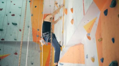 Bir adam yüksek bir duvar, yan görünüm tırmanıyor.