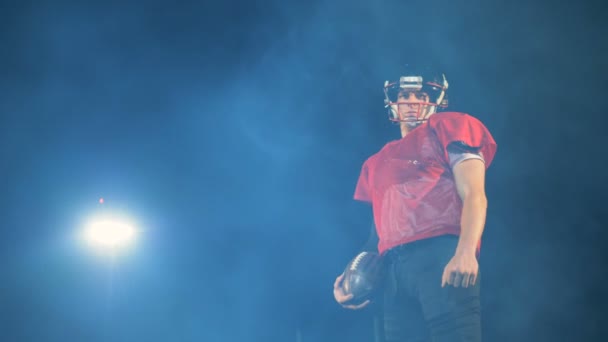 Professionell idrottsman poserar med en boll amerikansk fotbollsspelare på ett fält. — Stockvideo