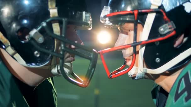 Jugadores de fútbol americano de pie cabeza a cabeza, vista lateral . — Vídeos de Stock