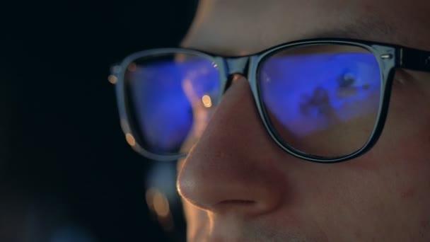 Un giocatore con gli occhiali che guarda un monitor, da vicino . — Video Stock