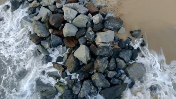 L'eau de mer avec de la mousse lave le littoral et les rochers dessus — Video