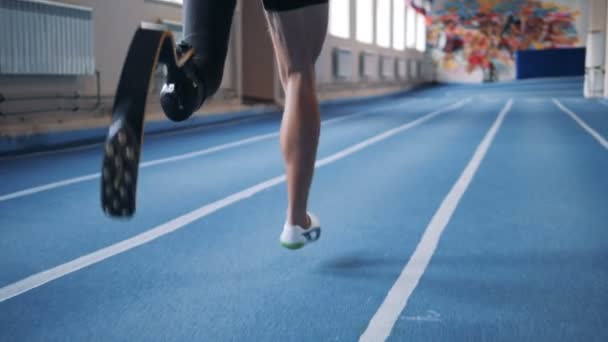 Un hombre corriendo en una pista con una pierna protésica, de cerca . — Vídeos de Stock