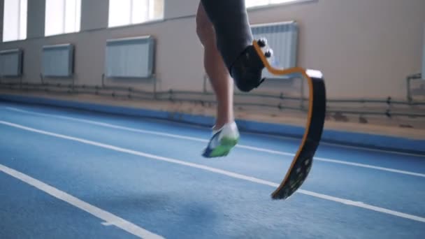 Esportista com perna biônica correndo em uma pista, vista lateral . — Vídeo de Stock
