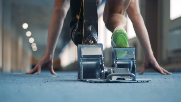 Hombre con prótesis de pierna biónica comienza a correr en una pista, vista posterior . — Vídeo de stock