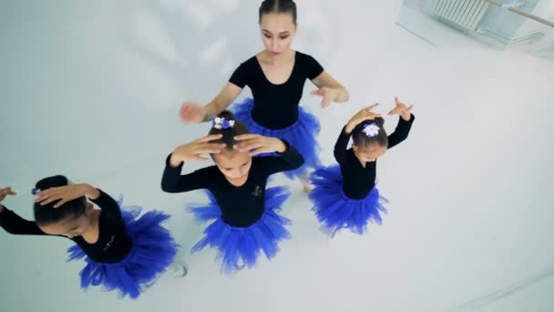 Vrouwelijke instructeur helpt kleine ballerina's aan het houden van houding — Stockvideo