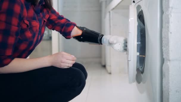 Одежда вынимается из стиральной машины дамой с бионической рукой — стоковое видео