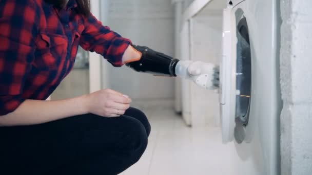 Clothes is getting taken out from the washing machine by a lady with a bionic arm — Stock Video