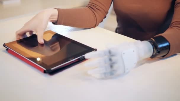 Eine Frau mit Roboterarm bedient ein Tablet — Stockvideo