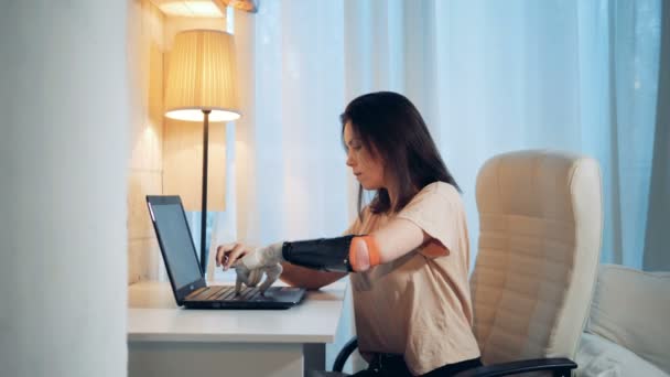 Молода жінка працює на ноутбуці з протезною рукою — стокове відео
