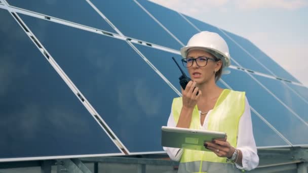 Un trabajador usa walkie-talkie cerca de paneles solares, de cerca . — Vídeos de Stock