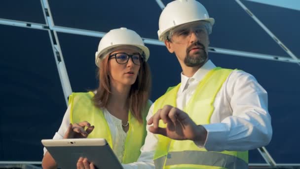 Solar ingenjörer arbetar med en platta nära solen batterier, närbild. — Stockvideo