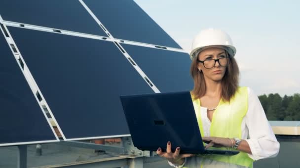 Mujer escribe en un ordenador portátil mientras camina cerca de las baterías de sol, de cerca . — Vídeos de Stock