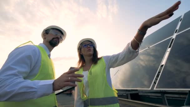 Man en vrouw praten in de buurt van zonnepanelen, close-up. — Stockvideo