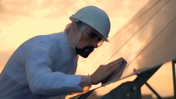 Un homme essuyant des panneaux solaires avec un chiffon, gros plan . — Video