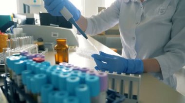 Bir laboratuvar odasında sıvı dökün, yakın çekim için bir kadın pipet kullanır.