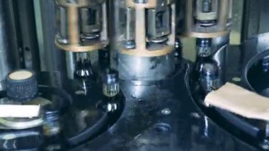 Cam şişe içecek ile dolu bir fabrika mekanizması tarafından taşınır