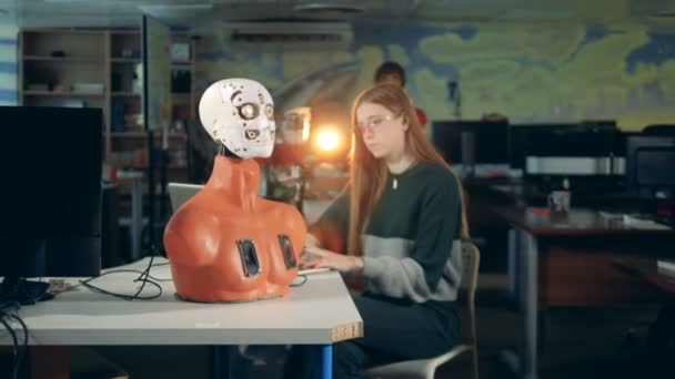 Una joven controla un robot en una mesa. Humanoide futurista e ingeniero . — Vídeos de Stock