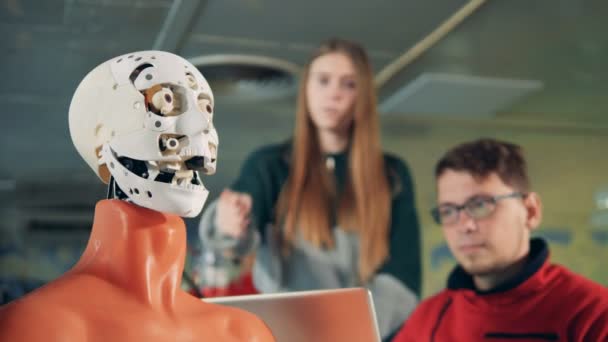 Ingenieros observando a un droide moviendo su rostro, de cerca . — Vídeos de Stock