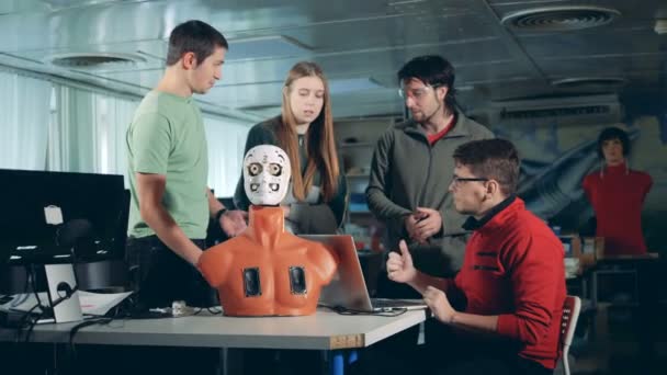 Quatre ingénieurs travaillant ensemble avec un humanoïde, un cyborg, un robot . — Video