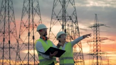 İki mühendis Etl yapıların önünde çalışıyoruz. Güç hattı yakınındaki sanayi işçileri.