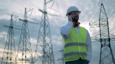 PhoneCall elektrik iletim hatları yanında duran erkek teknisyeni