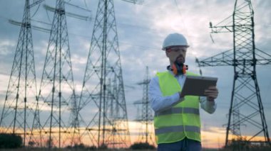 Enerji çalışan elektrik iletim hatları önünde bir tablet işletim