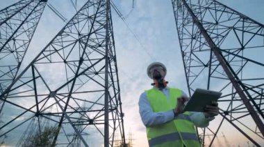 Uzun boylu elektrik kuleleri ve yanlarında çalışan bir erkek teknisyen