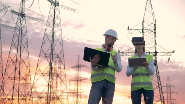 Lignes de transmission électriques et deux ingénieurs équipés d'ordinateurs travaillent avec un casque VR . — Video