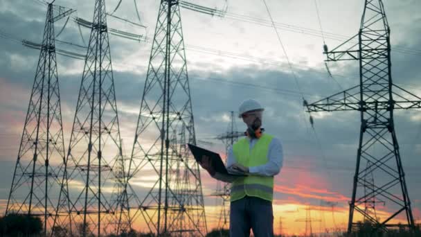 Paysage au coucher du soleil avec lignes électriques et un spécialiste masculin — Video