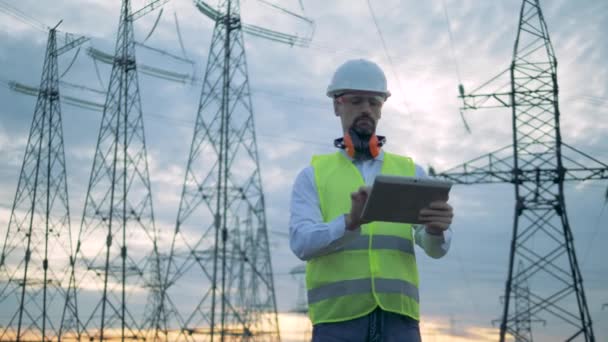 Ingeniero masculino está trabajando en una tableta mientras está cerca de líneas eléctricas — Vídeo de stock