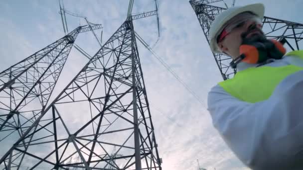 Hombre especialista está operando un ordenador entre las torres de electricidad — Vídeo de stock