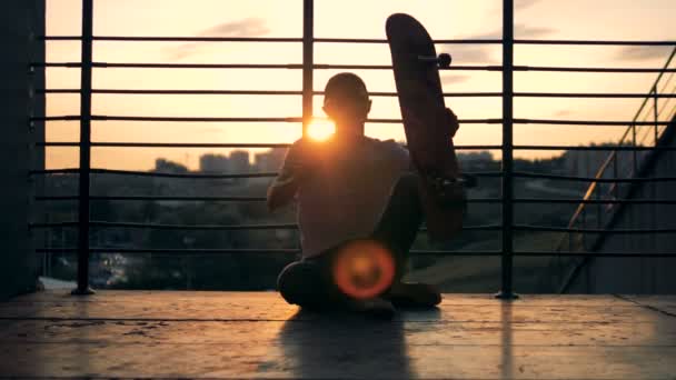 Hombre skater está sentado en el suelo y la reubicación de su monopatín — Vídeos de Stock