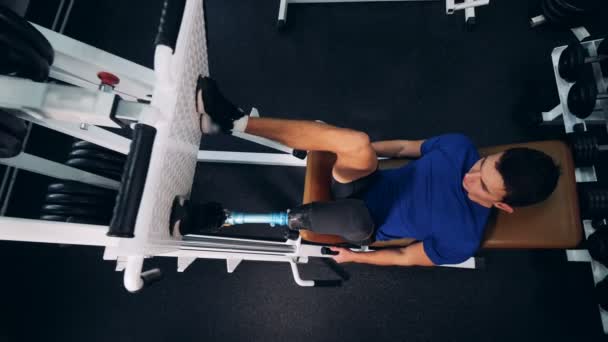 A pessoa levanta o peso com a perna protética em um ginásio, visão superior . — Vídeo de Stock