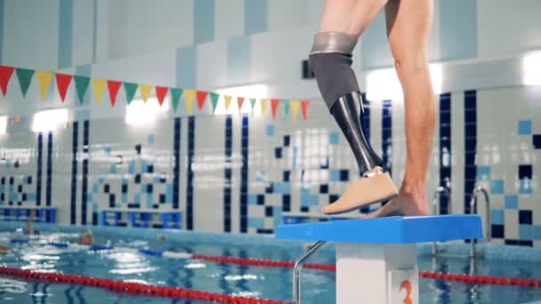 Nadador fica perto de uma piscina, vestindo prótese perna, close-up . — Vídeo de Stock