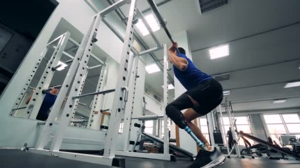 A man squats with a barbell, wearing prosthetic leg, bottom view. — Stock Video